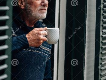 man drinkt koffie aan zijn raam